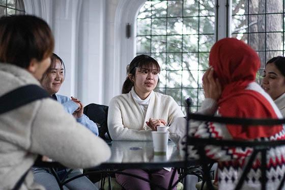 Photo of a group of international students seated in a room at Chatham University, talking together